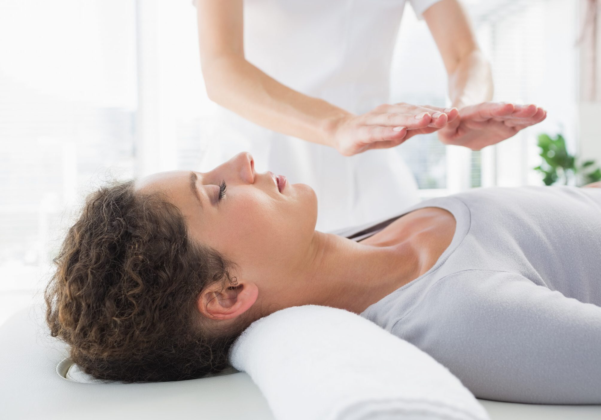 Attractive young woman having reiki treatment in health spa